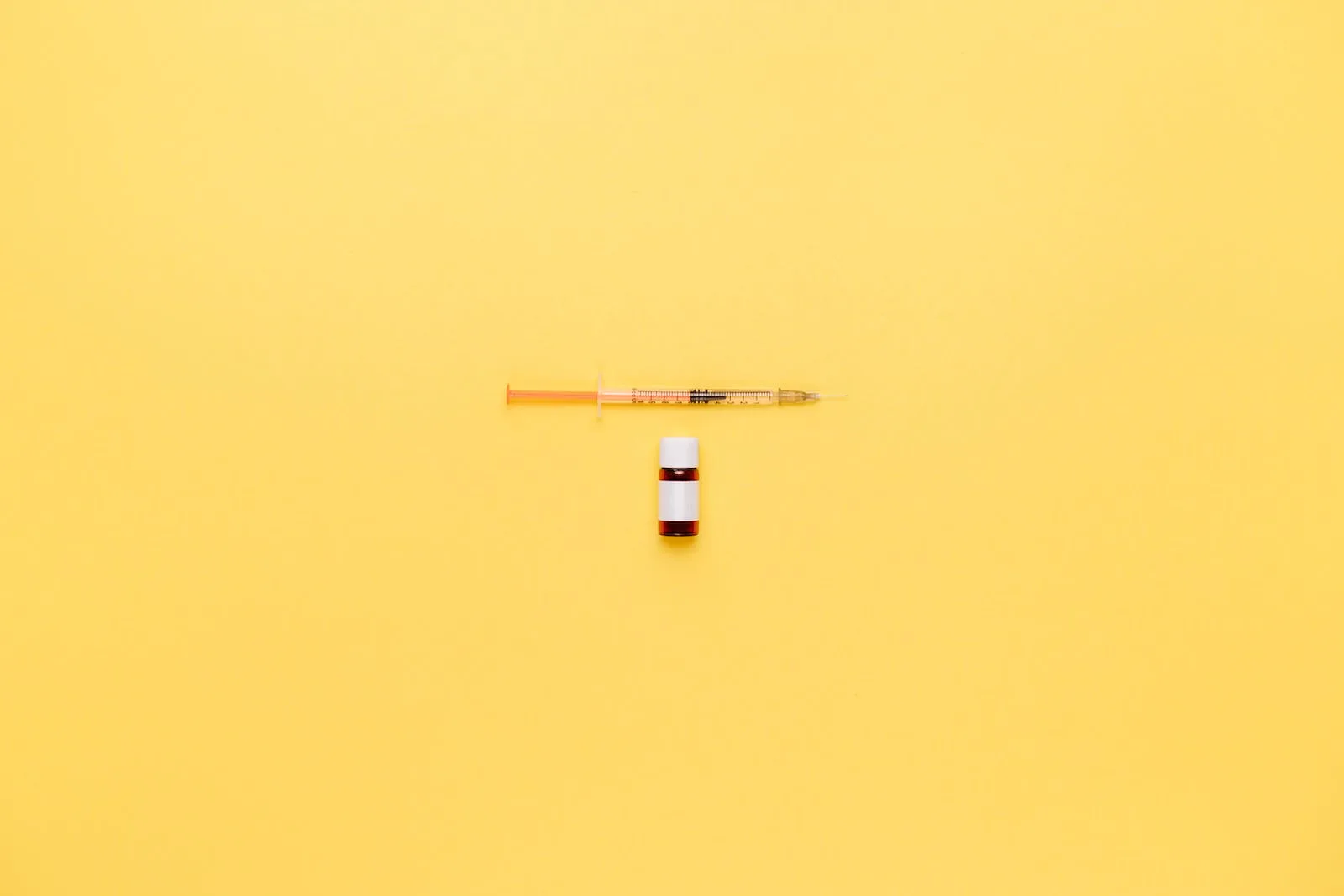 Vial And Syringe On Yellow Surface
